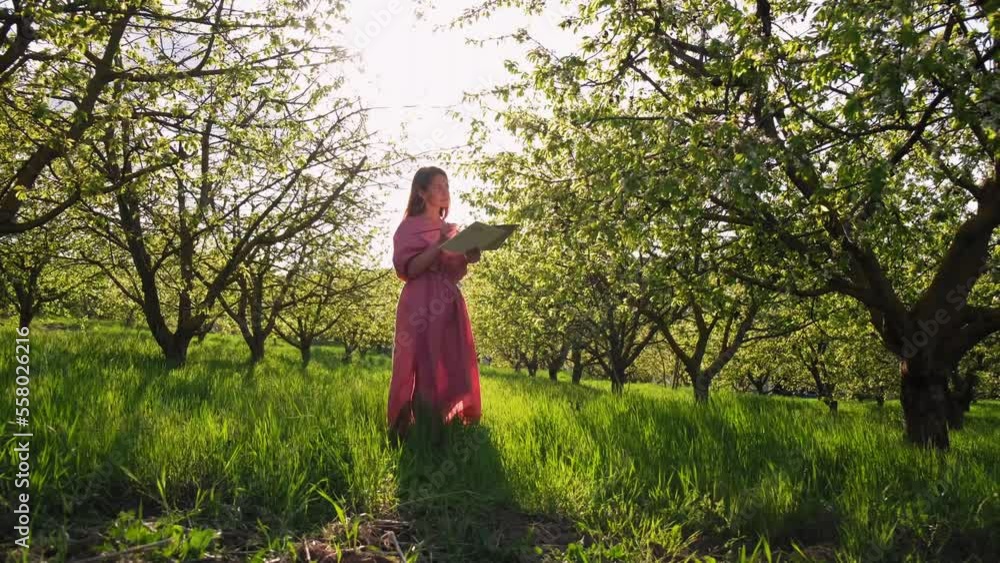 a girl at sunset paints in cherry orchards. The artist paints in the garden. Creative girl is painting a beautiful picture in the garden, holding a palette and brush, using tools to create a canvas. a girl at sunset paints in cherry orchards. The artist paints in the garden. Creative girl is painting a beautiful picture in the garden, holding a palette and brush, using tools to create a canvas.