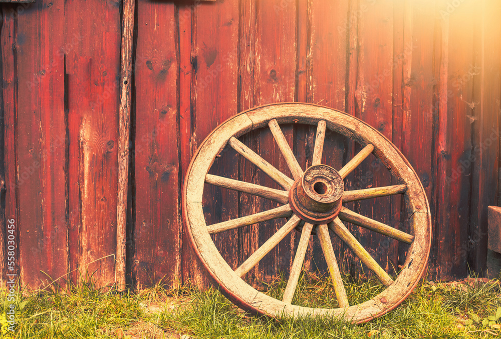 Old rusty wagon wheel leans against barn.Peasant tool. Old rusty wagon wheel leans against barn.Peasant tool.