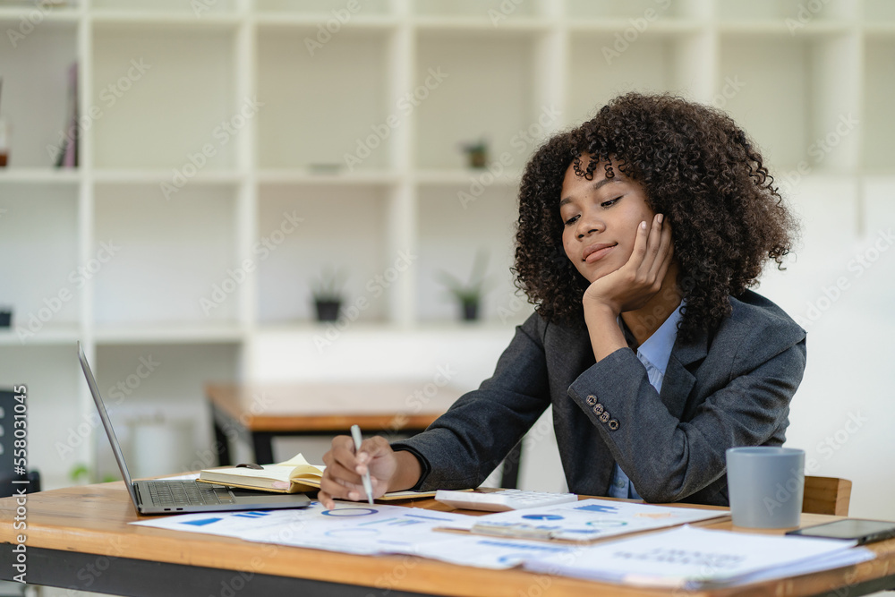 Young happy successful business woman working with laptop and calculating analytical calculator with financial graph document in office online meeting concept Young happy successful business woman working with laptop and calculating analytical calculator with financial graph document in office online meeting concept