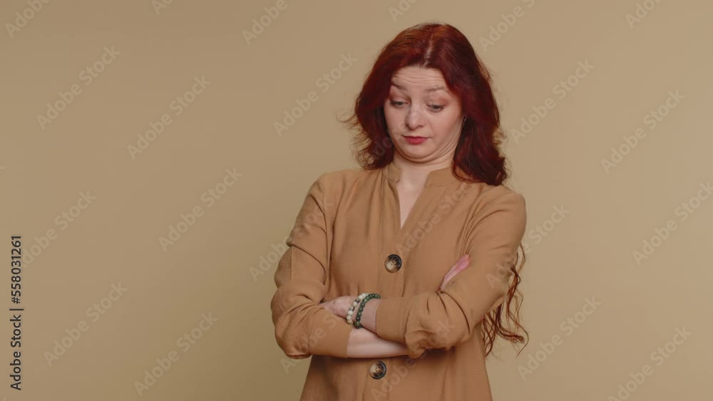Sad redhead woman tired bored indifferent expression, exhausted of tedious story, not interested in communication talk, displeasure, uninteresting. Young girl isolated alone on beige studio background Sad redhead woman tired bored indifferent expression, exhausted of tedious story, not interested in communication talk, displeasure, uninteresting. Young girl isolated alone on beige studio background