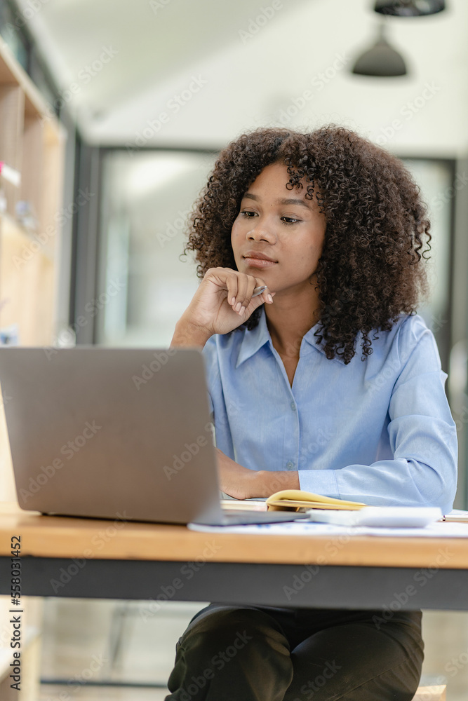 Young happy successful business woman working with laptop and calculating analytical calculator with financial graph document in office online meeting concept Young happy successful business woman working with laptop and calculating analytical calculator with financial graph document in office online meeting concept