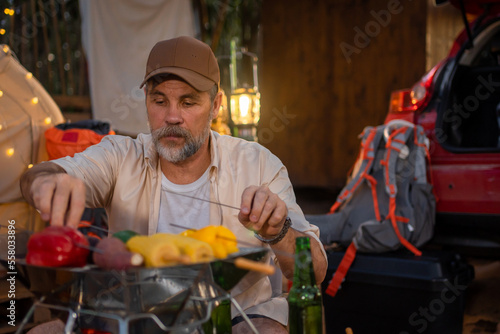 Elderly male tourists camping  toasting  grilling and drinking beer-alcohol for a fun  happy  summer party.