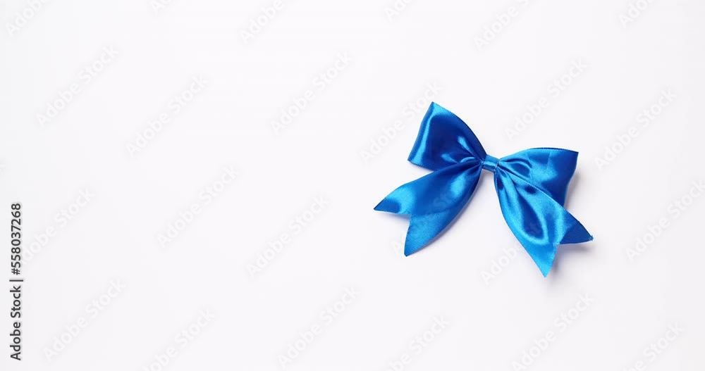 Detail of male hand placing ribbon in blue color over white background. Copy space. Detail of male hand placing ribbon in blue color over white background. Copy space.