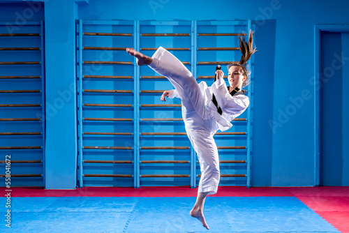 The karate woman with black belt. Sport woman fighting, poses punch in sport uniform dress. Taekwondo karate