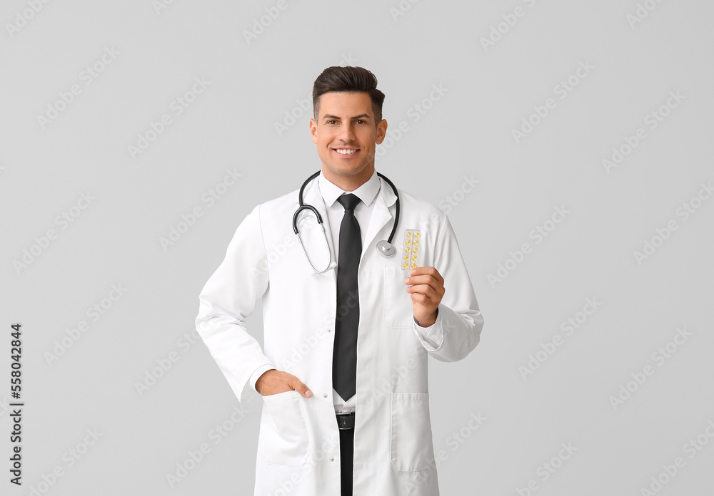 Male doctor with vitamins on light background Male doctor with vitamins on light background