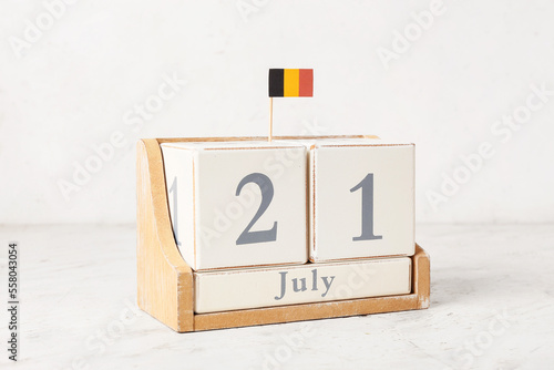 Cube calendar and small Belgian flag on table near light wall photo