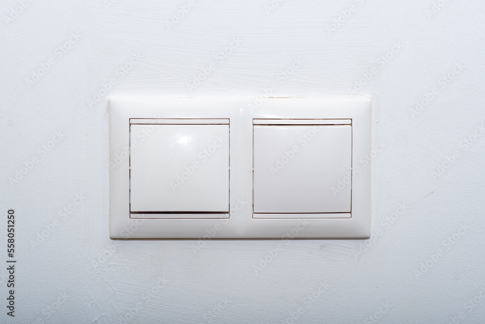 Standard light switch on the wall. Ordinary white plastic switches. Standard light switch on the wall. Ordinary white plastic switches.