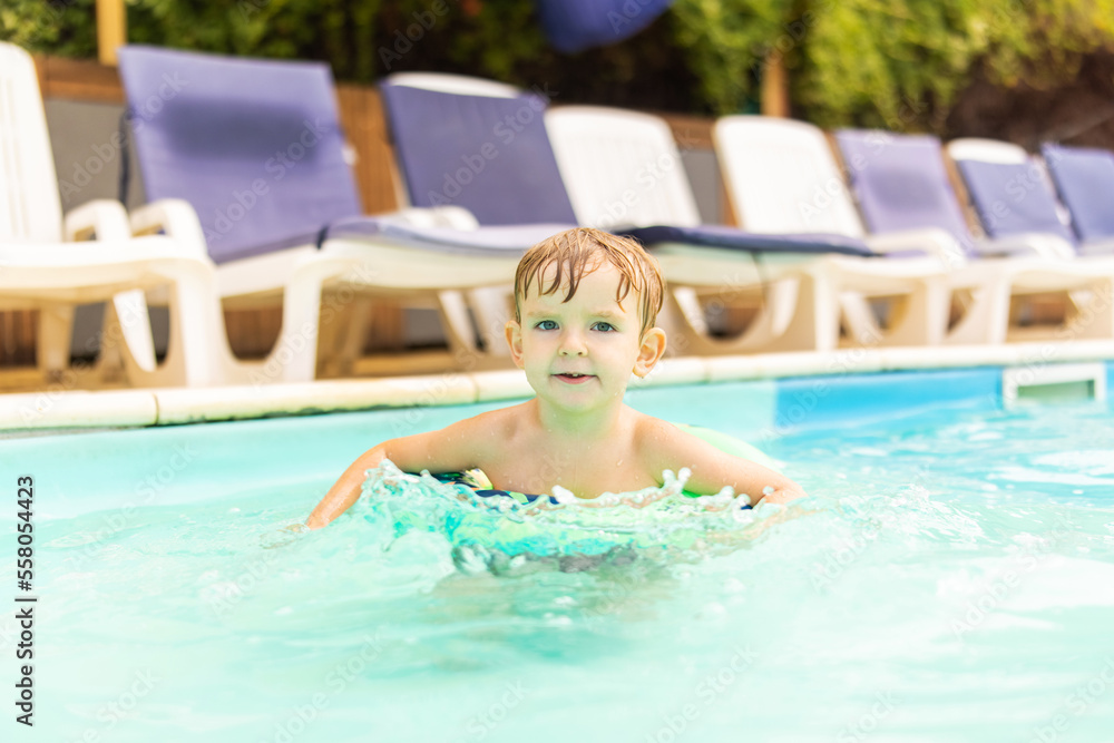 Child in swimming pool with inflatable circle enjoys summer vacation