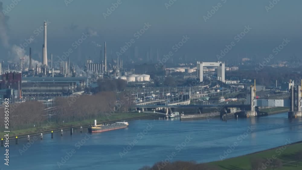 Aerial view of dense industrial center and oil refinery along a river outside the city of Rotterdam with the Botlek bridge and city in the background Aerial view of dense industrial center and oil refinery along a river outside the city of Rotterdam with the Botlek bridge and city in the background