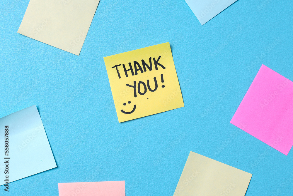 Top view of words thank you written on sticky note with colorful blank sticky notes for text space on blue background. Top view of words thank you written on sticky note with colorful blank sticky notes for text space on blue background.