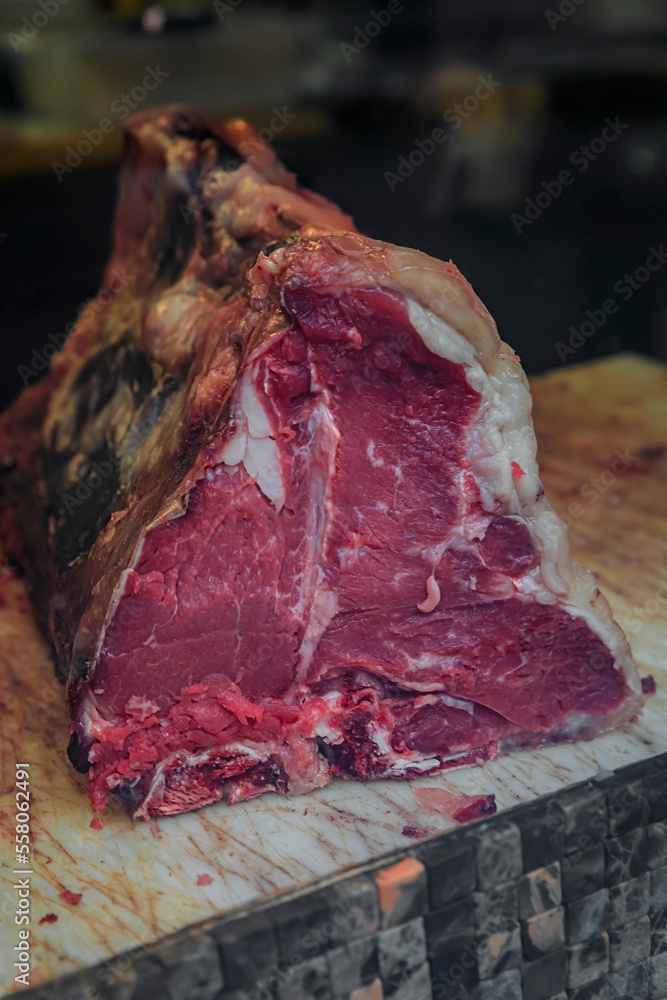 Classic uncut piece of dry aged T-bone Florentine steak from a Chianina cow on butcher table at a restaurant in Florence, Italy