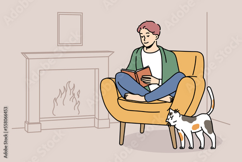 Happy young man sit in chair at home near fireplace reading book. Smiling guy relax in armchair enjoying literature. Hygge and domestic weekend. Vector illustration. 