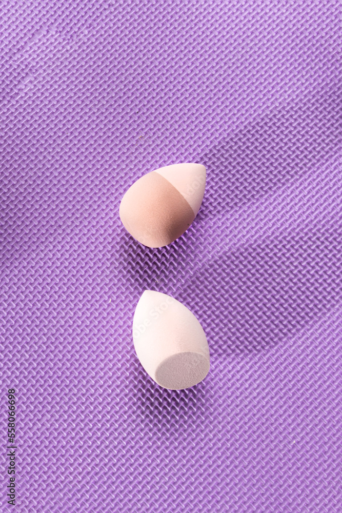 Two makeup sponges to apply foundation on a purple background