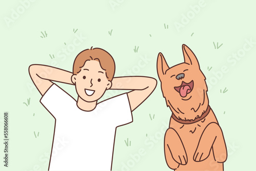 Smiling child lying on grass with dog 