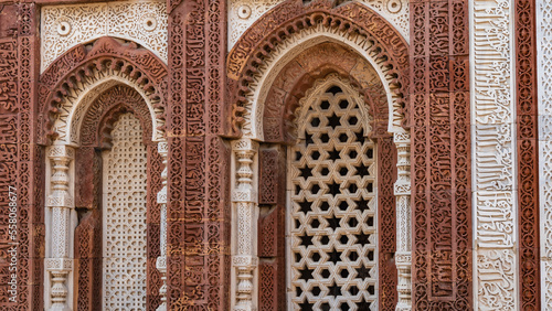 The ancient temple complex of Qutub Minar. Details. The facade is made of red sandstone and white marble decorated with carved ornaments. The arched windows have decorative stone grilles. India. Delhi