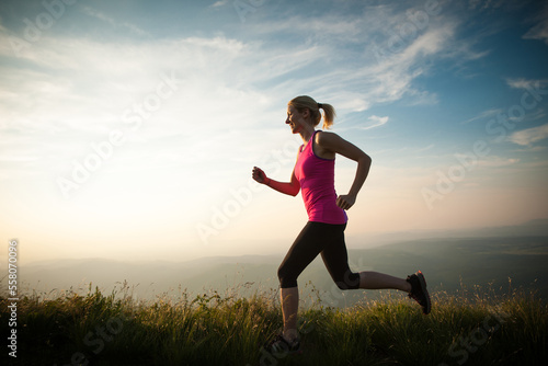beautiful young woman runns cross country on a mountian path at sunrise