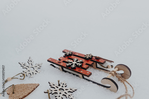 decorative red sledges stand on the snow, decorative snowflakes and a star, a heart lie nearby