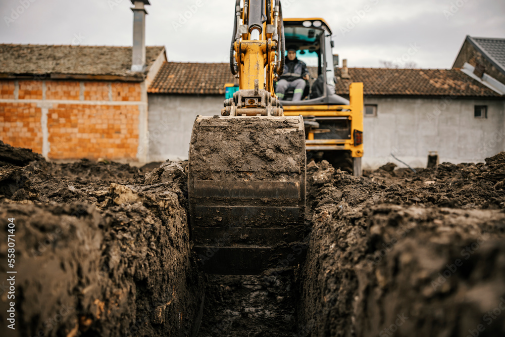 Fototapeta premium Close up of a digger digging foundation at construction site.