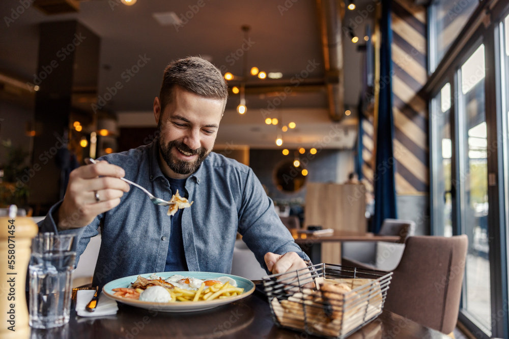 A happy man is eating breakfast at the restaurant. A happy man is eating breakfast at the restaurant.