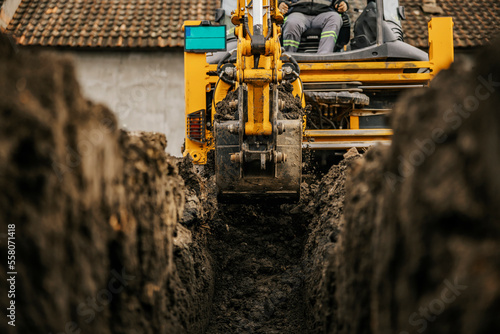 Cropped picture of a backhoe digging soil on construction site and making foundation.