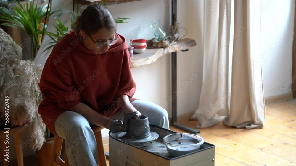 Professional female ceramic artist explaining how to work with clay on pottery wheel during masterclass, teaching students in ceramics school. Mindful activity and art therapy concept Professional female ceramic artist explaining how to work with clay on pottery wheel during masterclass, teaching students in ceramics school. Mindful activity and art therapy concept