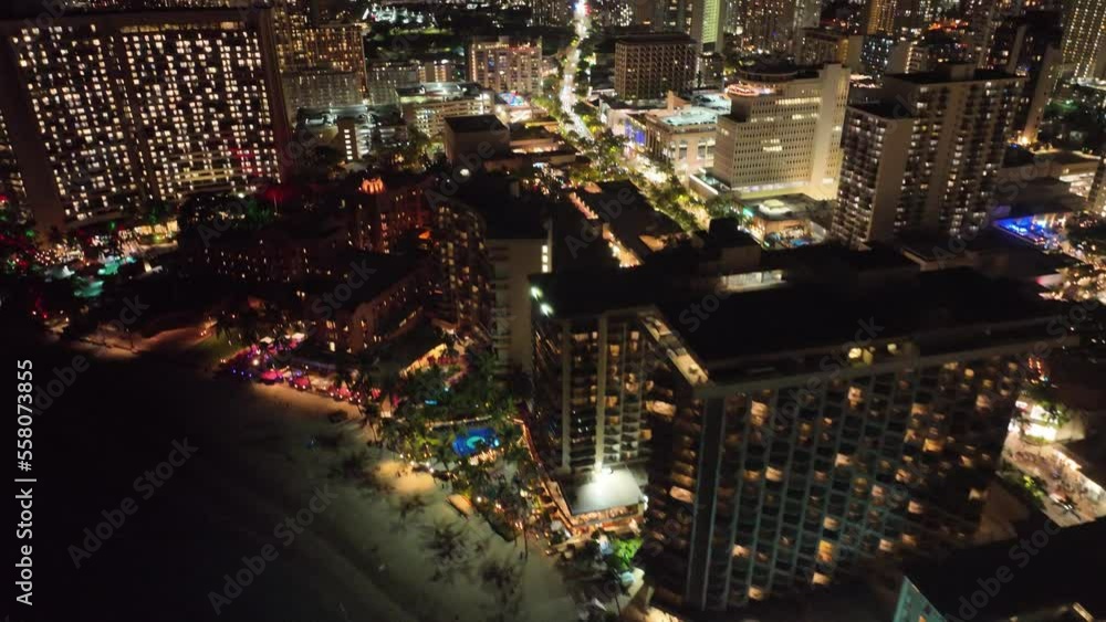 30 fps pan up of waikiki strip and skyline at night with traffic palm trees traffic in honolulu oahu hawaii on beach