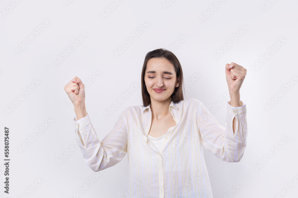 Happy young caucasian female wearing a white shirt clenched fist up for joy. Success and happiness of the work. Successful person, victory! Happy young caucasian female wearing a white shirt clenched fist up for joy. Success and happiness of the work. Successful person, victory!