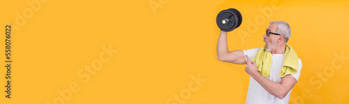 mature man with dumbbells on yellow background photo