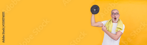 mature man with dumbbells on yellow background photo