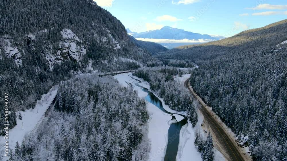 Experience the peaceful, serene beauty of Highway 1 with this stunning shot of a partially frozen Illecillewaet River and majestic mountains in Revelstoke. Captured during daylight under a blue sky Experience the peaceful, serene beauty of Highway 1 with this stunning shot of a partially frozen Illecillewaet River and majestic mountains in Revelstoke. Captured during daylight under a blue sky