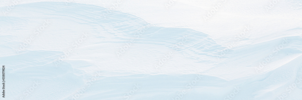 Wide panoramic winter background with snowy ground. Natural snow texture. Wind sculpted patterns on snow surface. Arctic, Polar region.