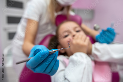 little scared girl covering her mouth with her hands while visiting the dentist.