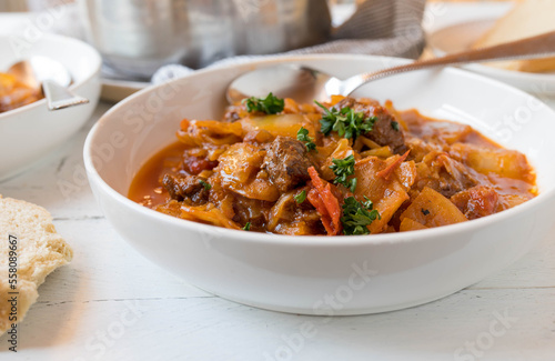 Beef stew with cabbage and vegetables in a bowl on kitchen table.