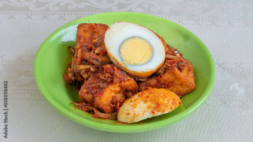 Balado egg sauce, chili sauce filled with eggs, anchovies, and tofu. Served in a bowl on a gray background. Selected focus.