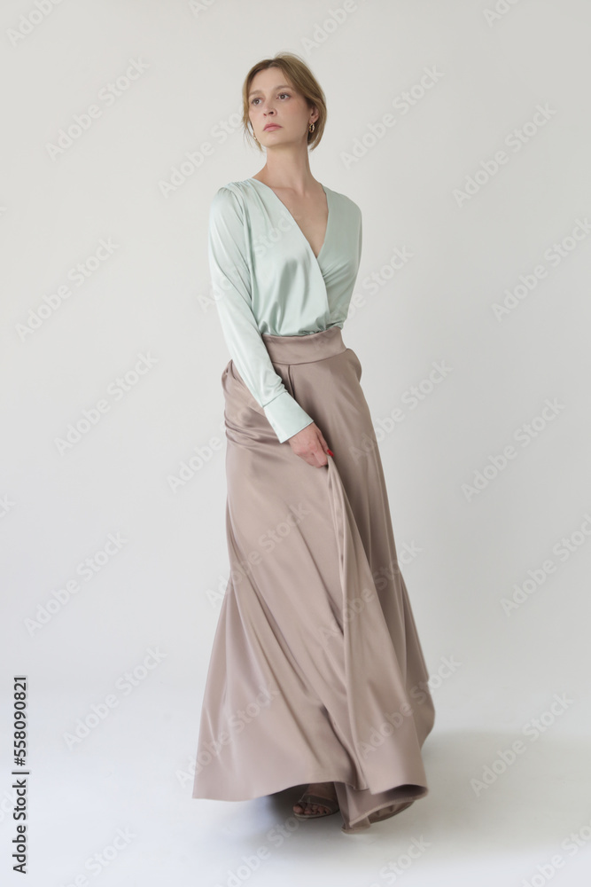 Studio shot of female fashion model in beige maxi circle skirt, Simplistic and elegant silk satin full length skirt Studio shot of female fashion model in beige maxi circle skirt, Simplistic and elegant silk satin full length skirt