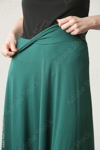 Serie of studio photos of young female model in comfortable yet stylish cotton outfit, black shit and emerald green skirt.