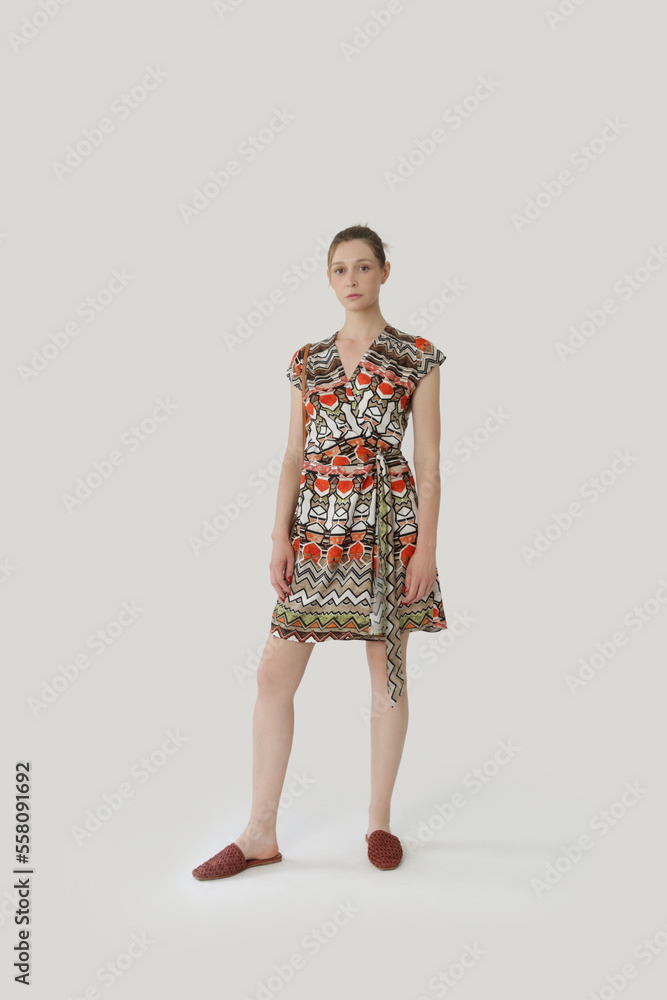 Serie of studio photos of young female model in colorful tropical print sleeveless wrap dress Serie of studio photos of young female model in colorful tropical print sleeveless wrap dress