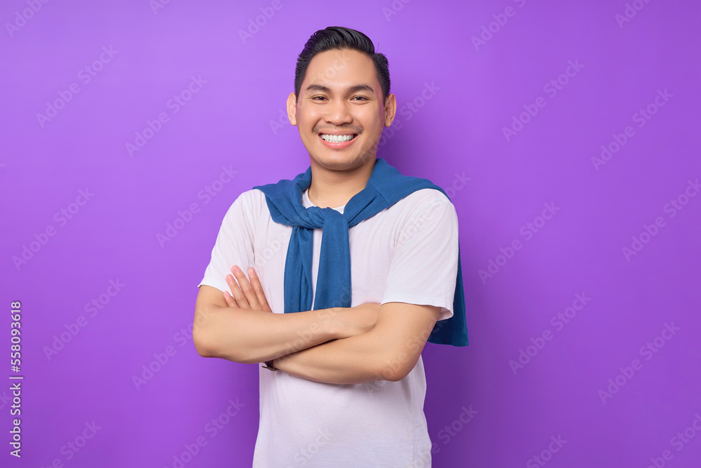attractive charming cheerful young Asian man wearing white t-shirt crossed hands and folded looking confident on camera isolated on purple background. People emotions lifestyle concept attractive charming cheerful young Asian man wearing white t-shirt crossed hands and folded looking confident on camera isolated on purple background. People emotions lifestyle concept