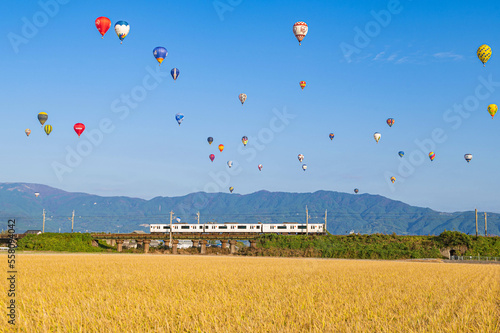 電車と快晴の空を飛行する熱気球