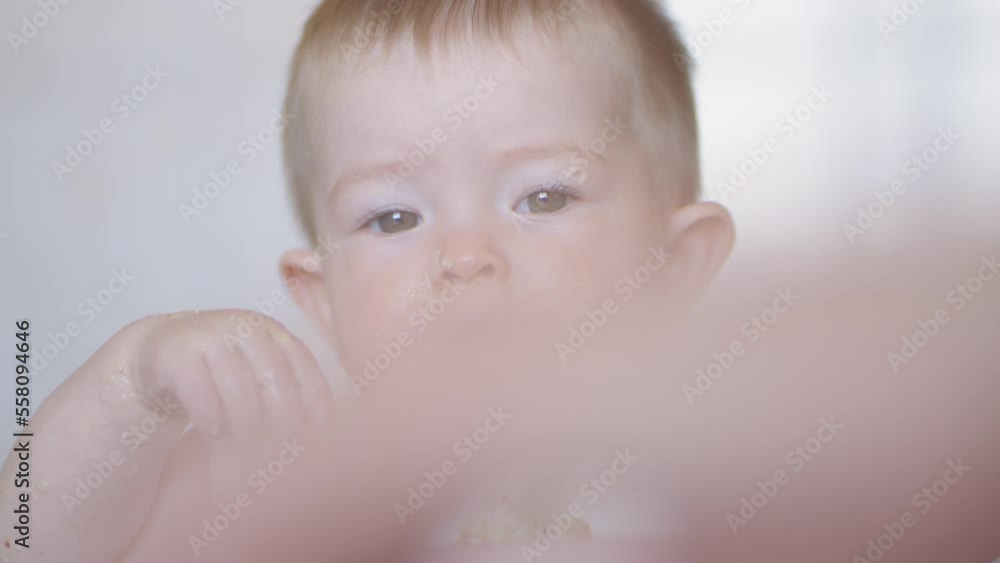 Emotions and impressions for the baby at the dinner table. Feeding a baby at the table. Porridge and fruits for breakfast for a charming girl. A small child eats breakfast on his own Emotions and impressions for the baby at the dinner table. Feeding a baby at the table. Porridge and fruits for breakfast for a charming girl. A small child eats breakfast on his own