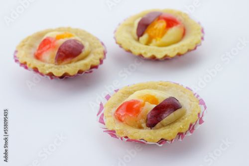 selective focus of mini fruit pie with orange slice and grape slices isolate on white background