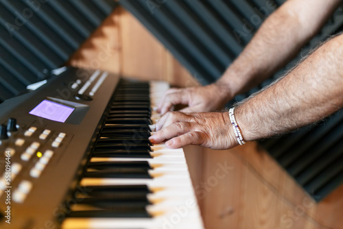Crop male musician playing on synthesizer