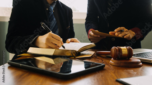 Business and lawyers discussing contract papers with brass scale on desk in office. Law, legal services, advice, justice and law concept picture with film grain effect