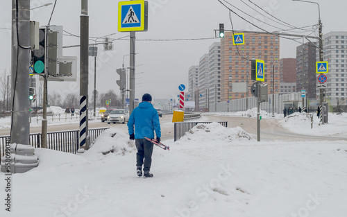 A man with skis walks on the sidewalk