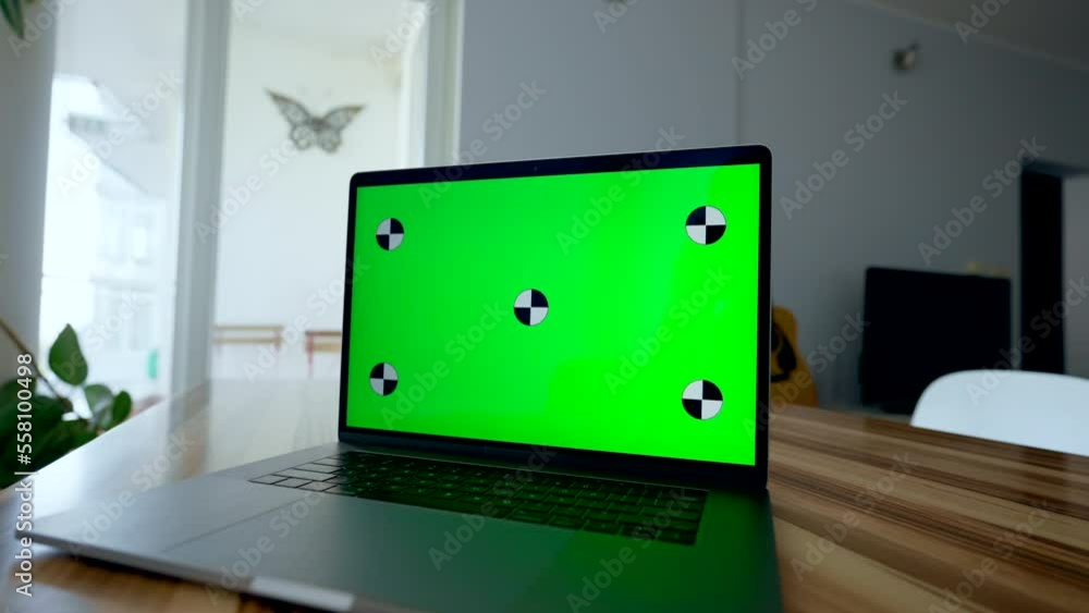 Modern laptop with chromakey screen stands on wooden table in living room. Innovative electronic device ready for freelance work at home closeup Modern laptop with chromakey screen stands on wooden table in living room. Innovative electronic device ready for freelance work at home closeup