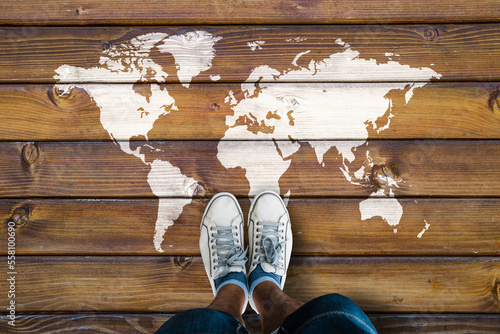 World map on a wooden floor and man in shoes
