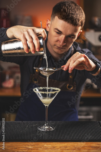 Bartender carefully filters alcoholic cocktail