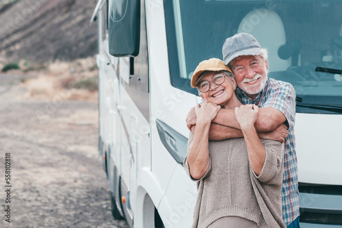 Foto Beautiful senior couple on leisure travel embracing affectionately while standing outside their motorhome