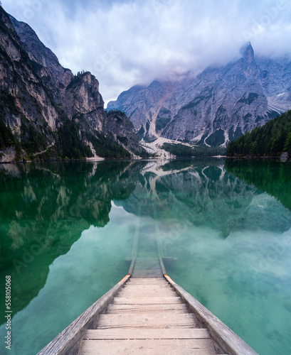 Holz Treppe in einen grünen und türkisen Bergsee in dem sich Berge spiegeln.