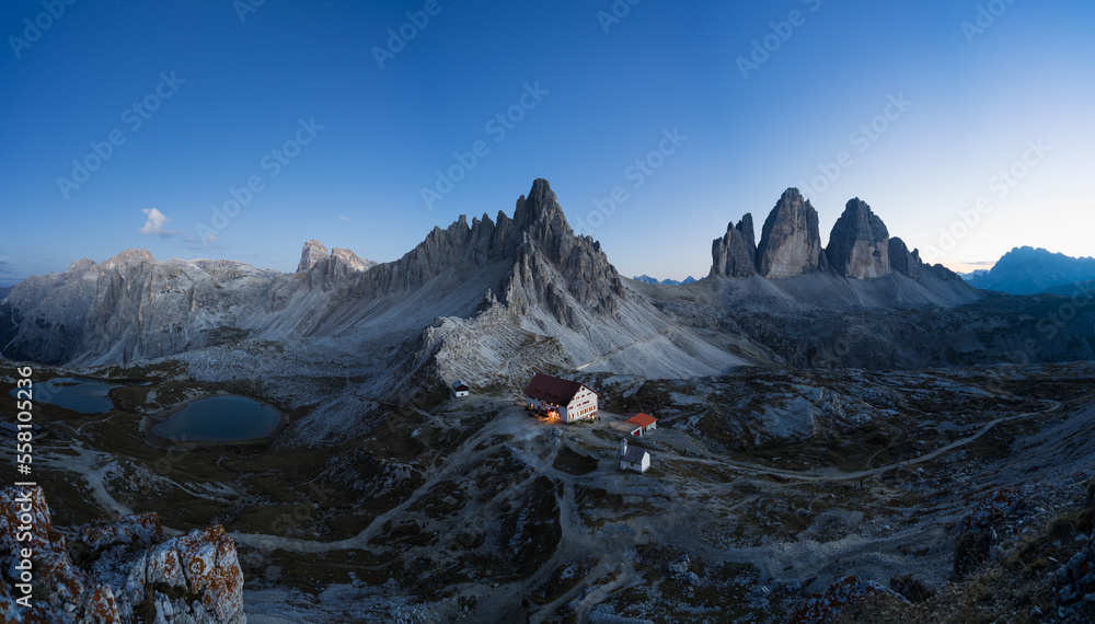 Fototapeta premium Panorama der Drei Zinnen mit Hütte zur blauen Stunde.
